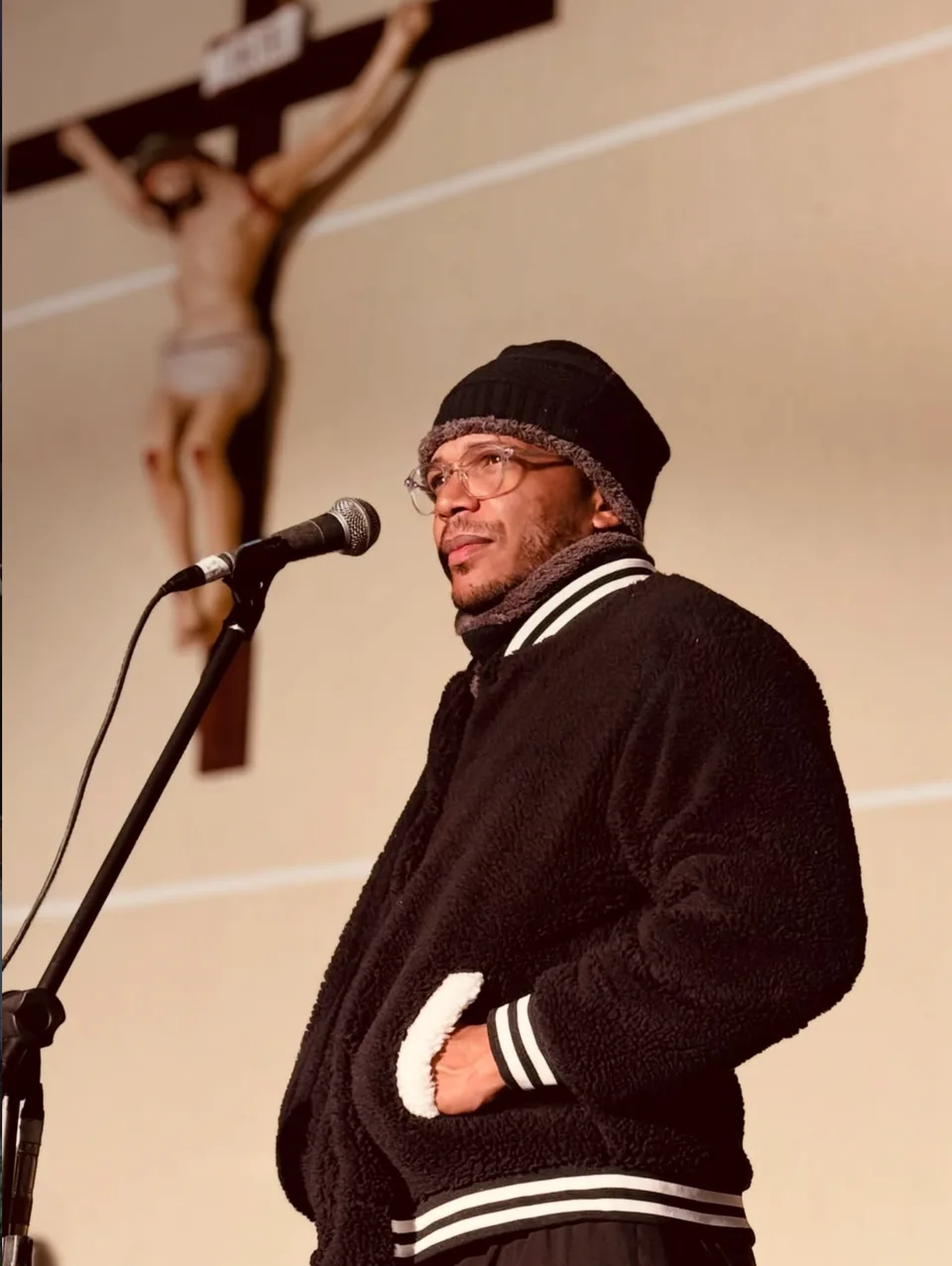 Lukas Cruz cantando diante de um crucifixo